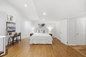Finished basement bedroom with sitting area and wood-look flooring.