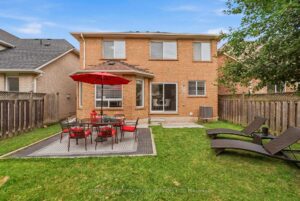 Rear exterior of the home featuring a private fenced backyard, patio, and spacious lawn.