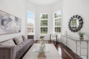 Bright living room with hardwood flooring, oversized windows, and elegant décor.