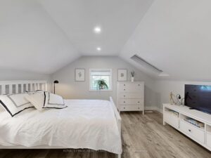 Spacious loft-style primary bedroom with sloped ceiling and large window.