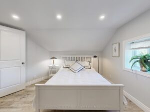 Bright primary bedroom with modern flooring, dresser, and neutral finishes.