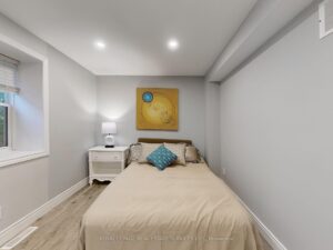 Comfortable bedroom with large window, modern flooring, and neutral décor.