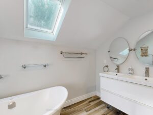 Elegant bathroom vanity with skylight, modern fixtures, and freestanding bathtub.