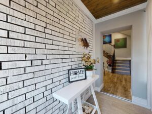 Welcoming front entry featuring painted brick accent wall and decorative console table.