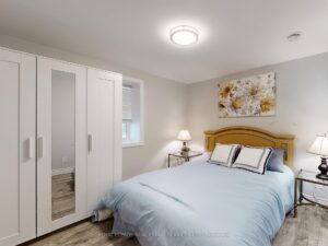 Bright bedroom with mirrored closet doors, neutral finishes, and modern lighting.