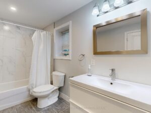 Contemporary four-piece bathroom with vanity, bathtub, and marble-look tile surround.