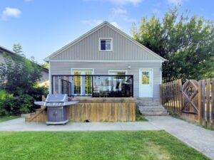 Fully fenced backyard with spacious wood deck, barbecue area, and mature trees.