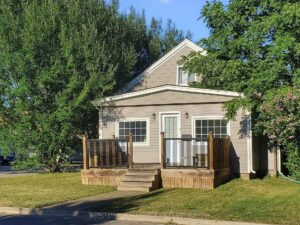 Charming detached home with covered front porch, mature landscaping, and inviting curb appeal.