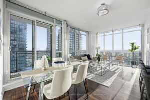 Bright open-concept living and dining area with floor-to-ceiling windows and city views.