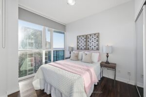Bright secondary bedroom with large window and hardwood flooring.