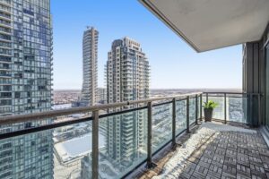 Private covered balcony with glass railings and panoramic city views.