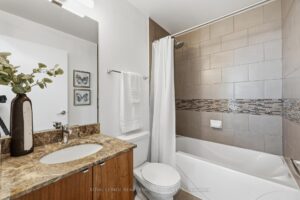 Four-piece bathroom with granite vanity and tiled bathtub surround.