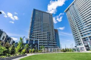 Exterior view of the modern condominium towers with landscaped grounds and blue sky.