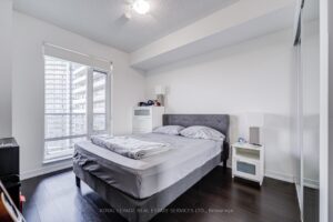 Primary bedroom with large window, modern flooring, and neutral finishes.