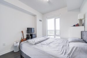 Bedroom with floor-to-ceiling window offering beautiful city views.