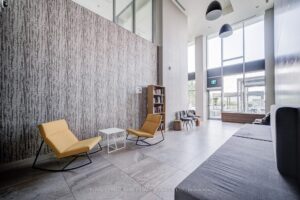 Bright condominium lobby with double-height windows and comfortable seating area.