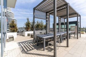 Rooftop outdoor dining area beneath pergolas overlooking the surrounding neighbourhood.