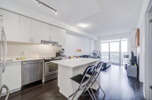 Bright open-concept kitchen with quartz island, stainless steel appliances, and balcony access.