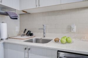 Kitchen workspace with undermount sink, quartz countertops, and subway tile backsplash.