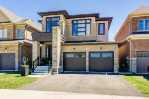 Modern two-storey detached home with stone and brick exterior, covered front porch, and double garage.