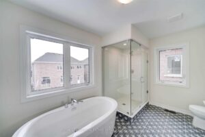 Luxury ensuite bathroom featuring a freestanding soaker tub, glass walk-in shower, and designer tile flooring.