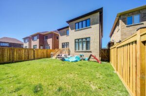 Fully fenced backyard with green lawn, wooden privacy fence, and space for outdoor entertaining.