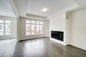 Sun-filled family room with sleek fireplace, hardwood floors, and expansive rear-facing windows.