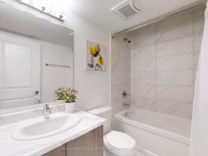 Modern 4-piece bathroom with vanity, bathtub, and marble-look tile surround.
