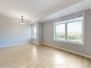 Bright open-concept living room with large windows, luxury vinyl flooring, and abundant natural light.