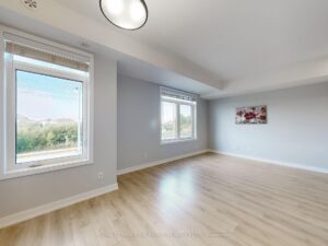 Open living room with expansive windows overlooking green space and contemporary finishes.