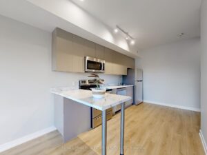 Modern kitchen with breakfast bar, quartz countertops, stainless steel appliances, and open dining area.