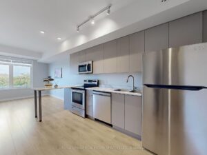 Open-concept kitchen with breakfast peninsula, stainless steel appliances, and spacious living area beyond.