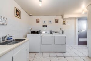 Common laundry facility with commercial washers, dryers, and utility sink for residents.
