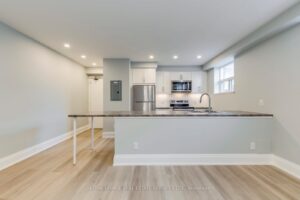 Renovated apartment kitchen featuring white cabinetry, stainless steel appliances, large island, and modern finishes.