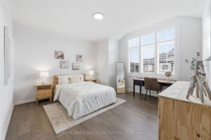Spacious primary bedroom with hardwood flooring, plantation shutters, and a bright sitting area.