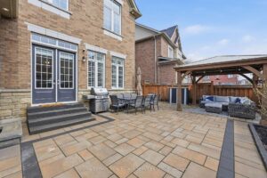 Private interlock patio with outdoor seating, pergola, and fully fenced backyard.