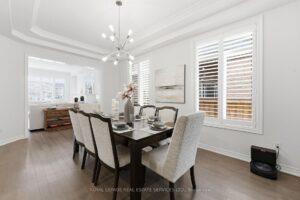 Formal dining room with elegant chandelier, large windows, and contemporary finishes.