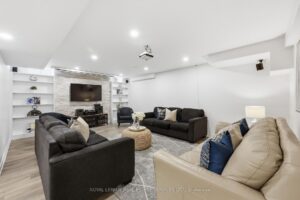 Finished basement recreation room with recessed lighting, comfortable seating, and built-in shelving.