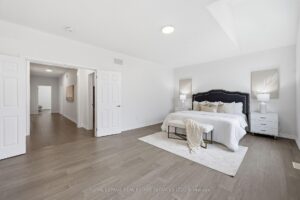 Spacious bedroom with hardwood flooring, large windows, and neutral finishes.