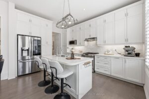 Modern chef's kitchen with white cabinetry, centre island, quartz countertops, and stainless steel appliances.