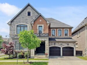 Front elevation of a luxury stone and brick home with double garage and landscaped front yard.