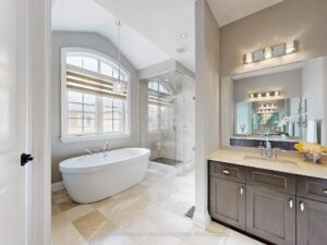 Spa-inspired primary ensuite with freestanding soaker tub, double vanity, and large arched window.