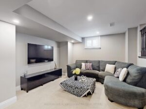 g Finished basement recreation room with modern seating area, recessed lighting, and wall-mounted television.