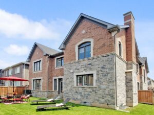 Rear exterior of the detached home with fully fenced backyard and stone patio.