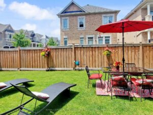 Private backyard featuring a spacious lawn, patio, and outdoor dining area with umbrella.