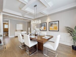 Elegant formal dining room with coffered ceiling, chandelier, and decorative wall mouldings.