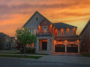 Twilight exterior of the luxury detached home with illuminated architectural lighting.