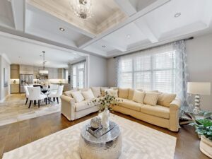 Bright family room with coffered ceiling, gas fireplace, and large windows.