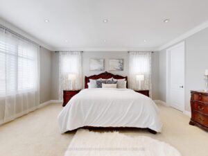 Spacious primary bedroom with tray ceiling, plush carpeting, and oversized windows.