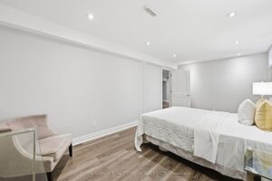 Spacious lower-level bedroom with recessed lighting and neutral finishes.